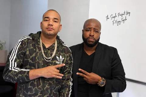 Vern Harris and DJ Envy at the New York launch, photographed against a wall with black script
