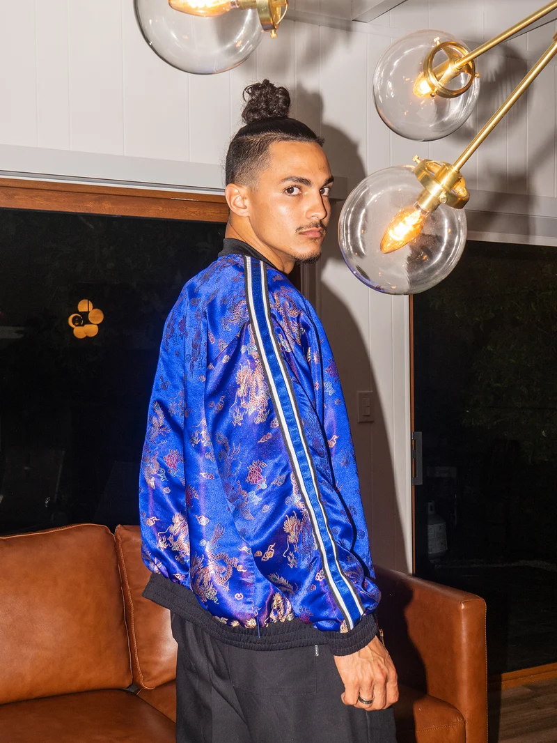 Side and back view of a model in a cobalt brocade bomber indoors