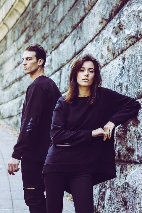 Two New York campaign models wearing black looks beside a stone wall