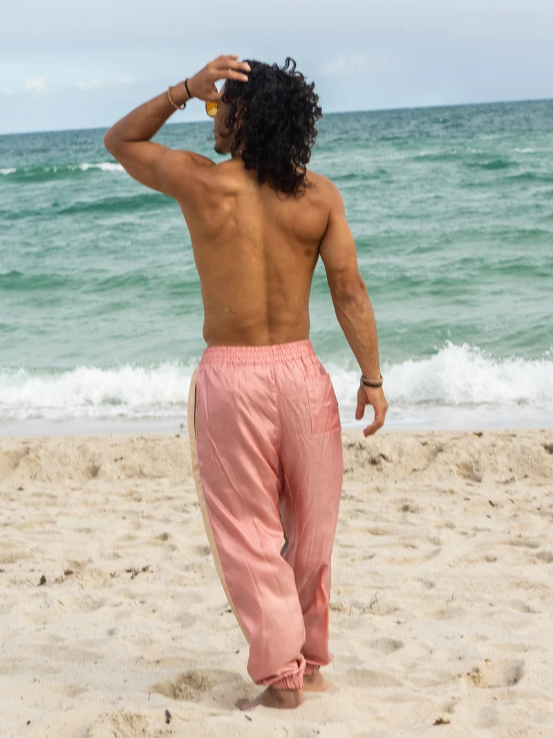 Back view on the beach of a model in pink satin trousers