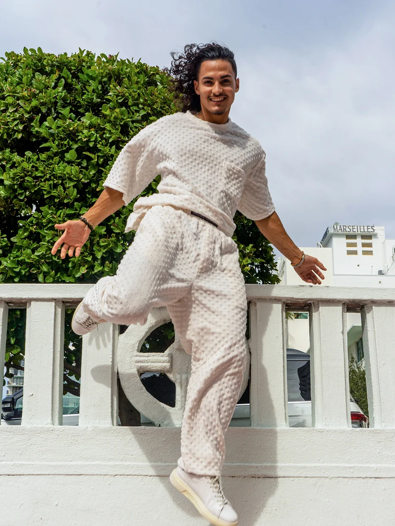 Model jumping mid-air in a white textured set