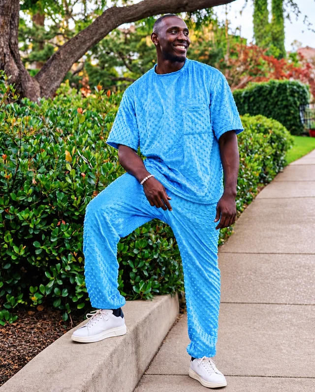 Smiling model in a blue outfit standing on a clean paved street