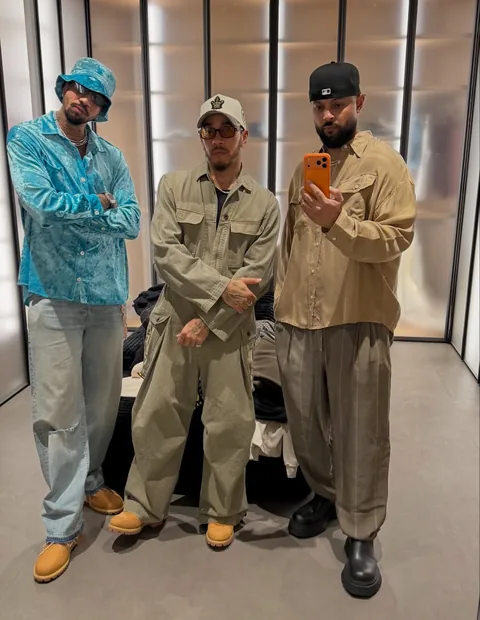 Miles Chamley-Watson in a blue shirt and matching bucket hat alongside Lewis Hamilton and another person during Coachella weekend
