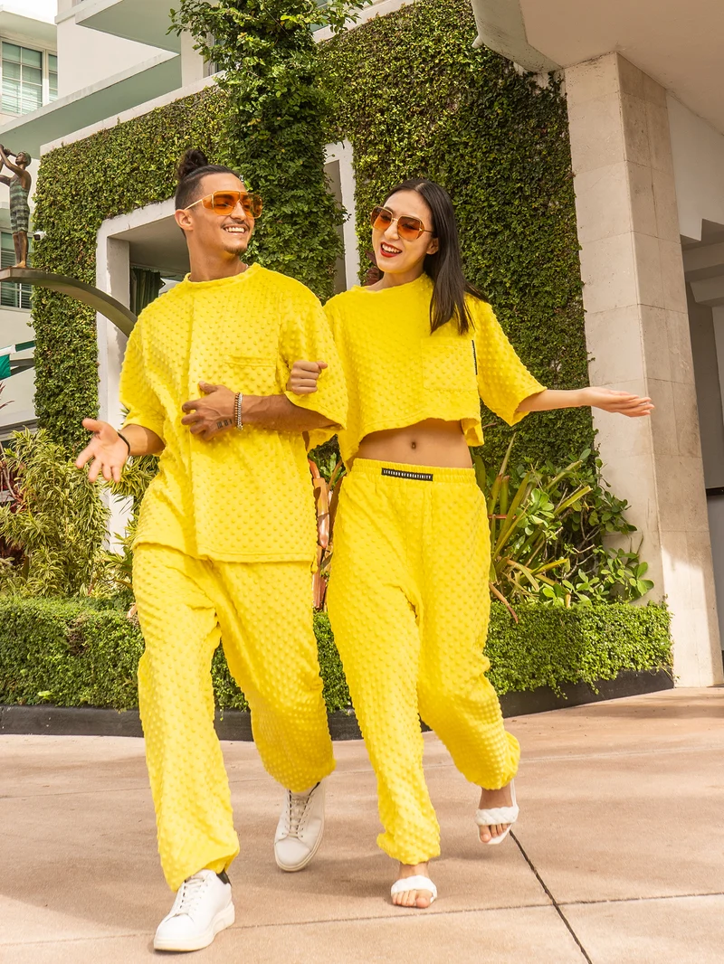 Couple walking together in matching yellow textured sets and amber sunglasses