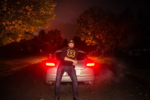 Toronto nighttime campaign portrait in a black graphic sweatshirt beside a car