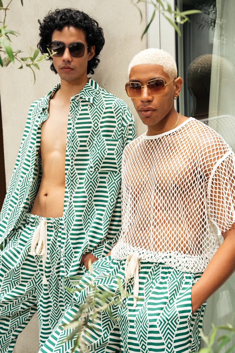Portrait of two models in green and white geometric-print sets, one in a white mesh top, both in sunglasses
