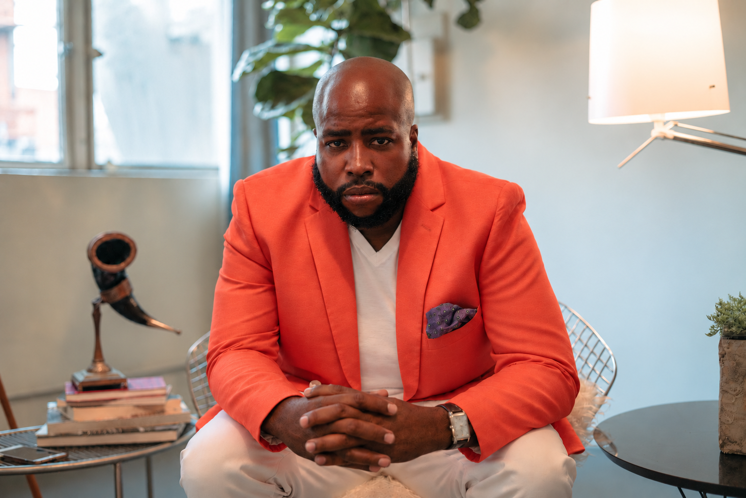 Vern Harris seated in a coral jacket and white trousers