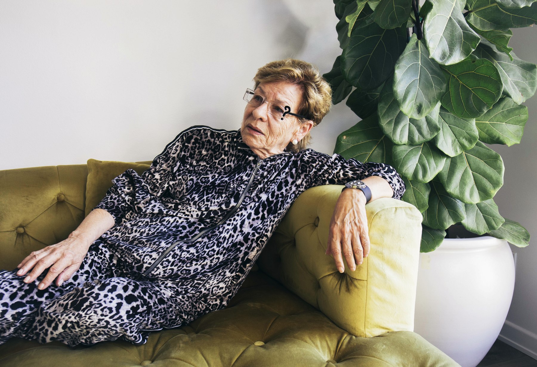 Model reclining on a green sofa in a black-and-white patterned LOC outfit