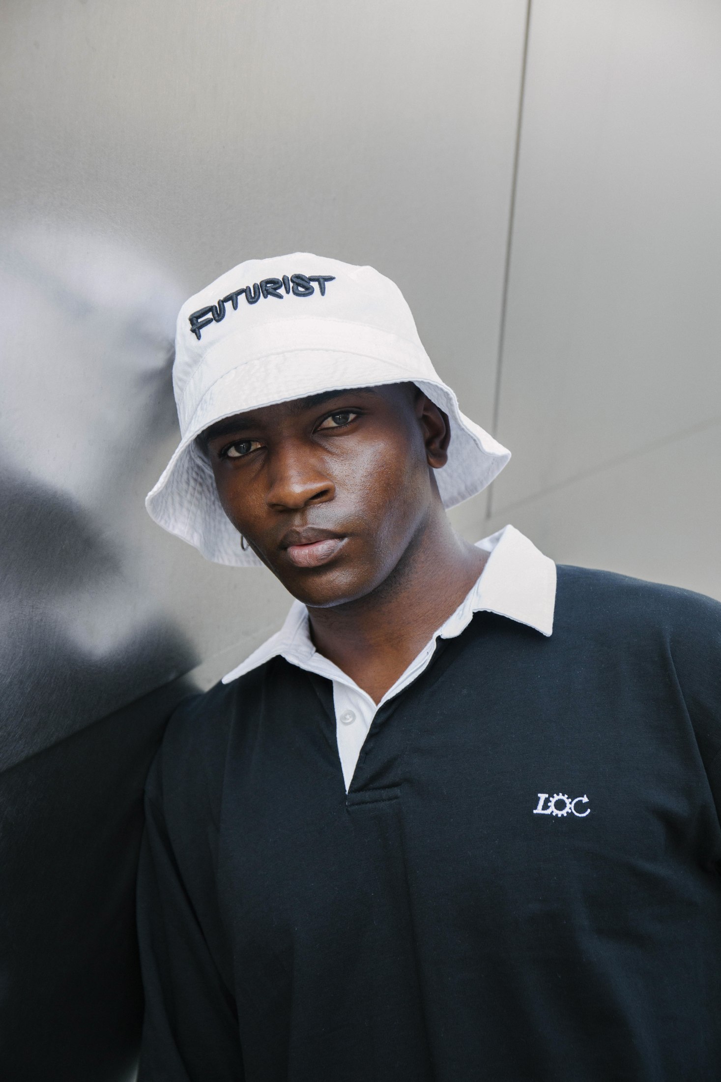 Portrait of a model wearing a dark collared LOC shirt and white cap
