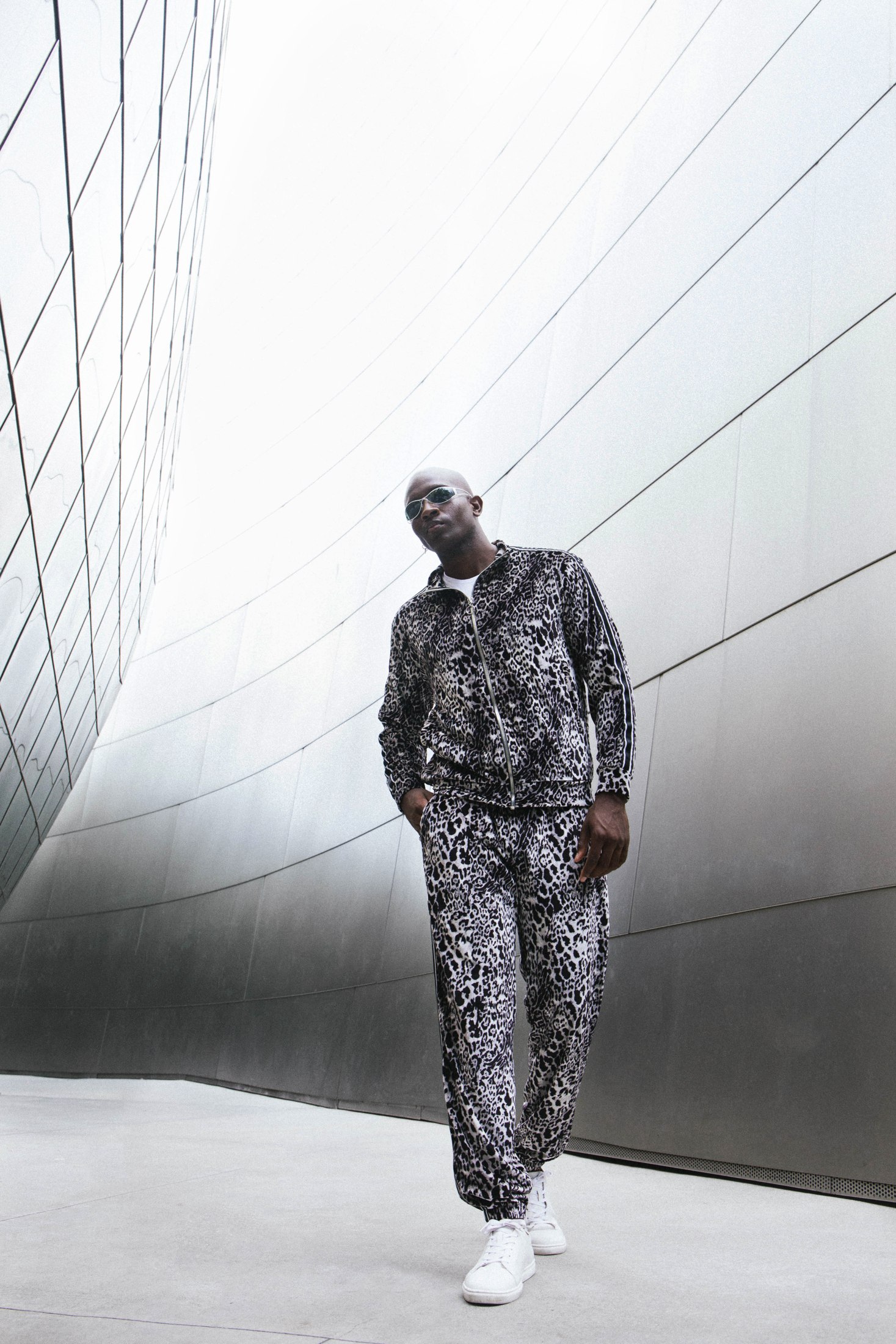 Model in a black-and-white patterned LOC set walking beside a curved metal wall