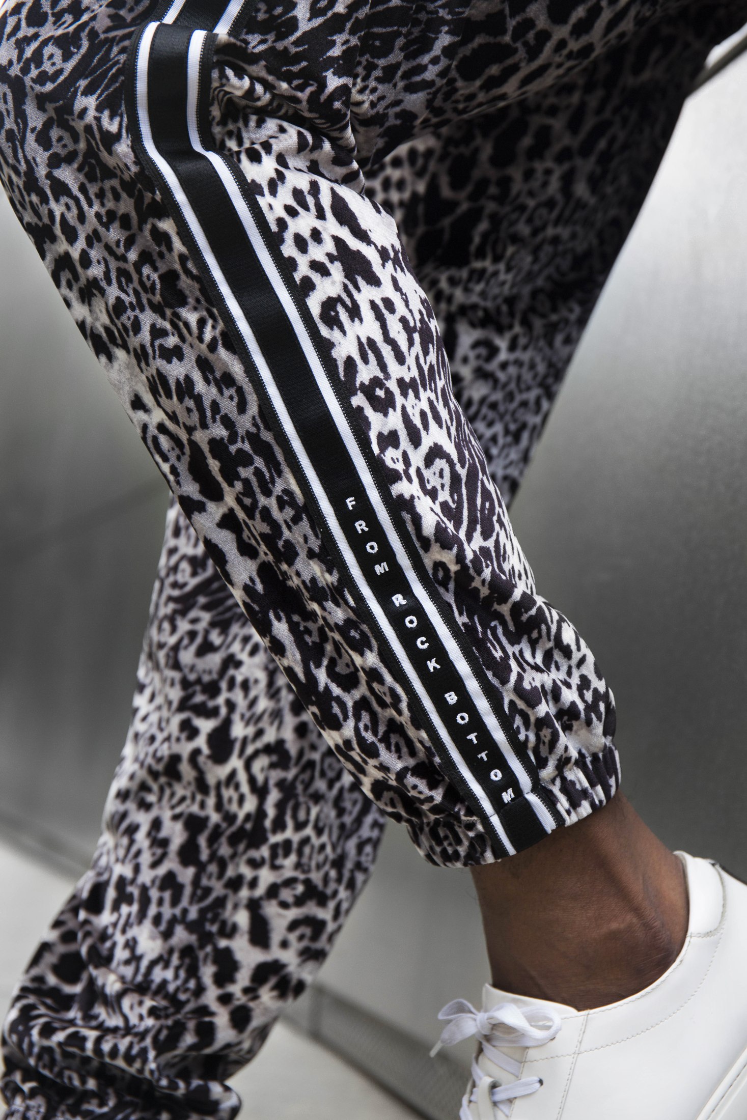 Close-up of patterned LOC trousers with striped side trim and white sneakers