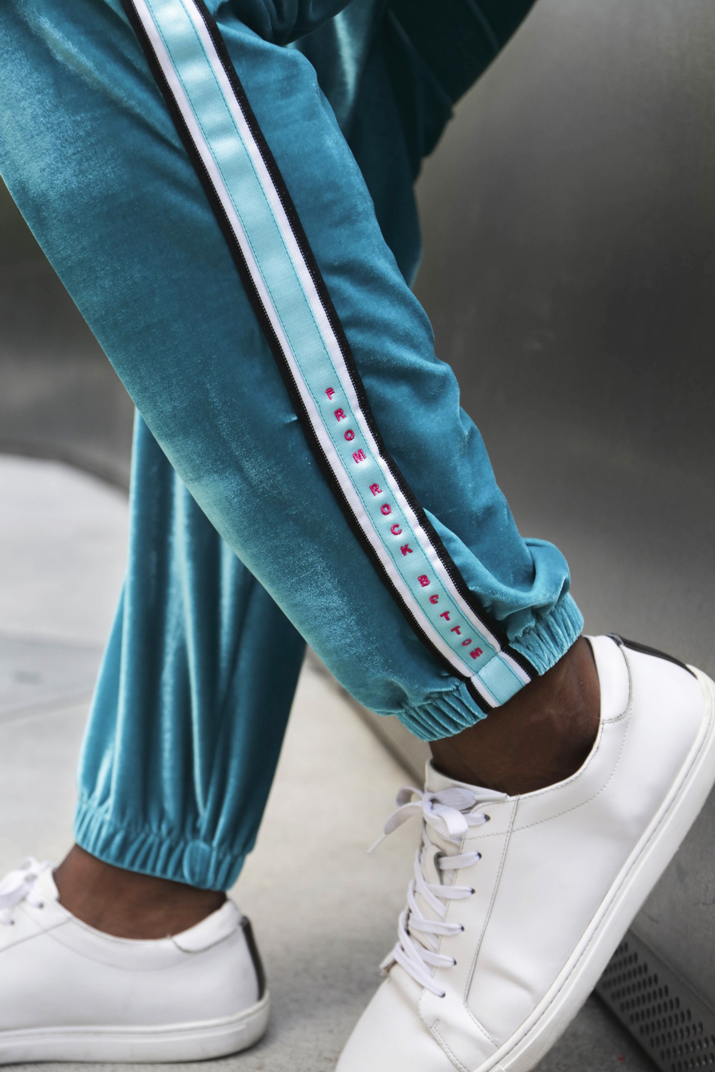 Detail of turquoise LOC track pants and white sneakers