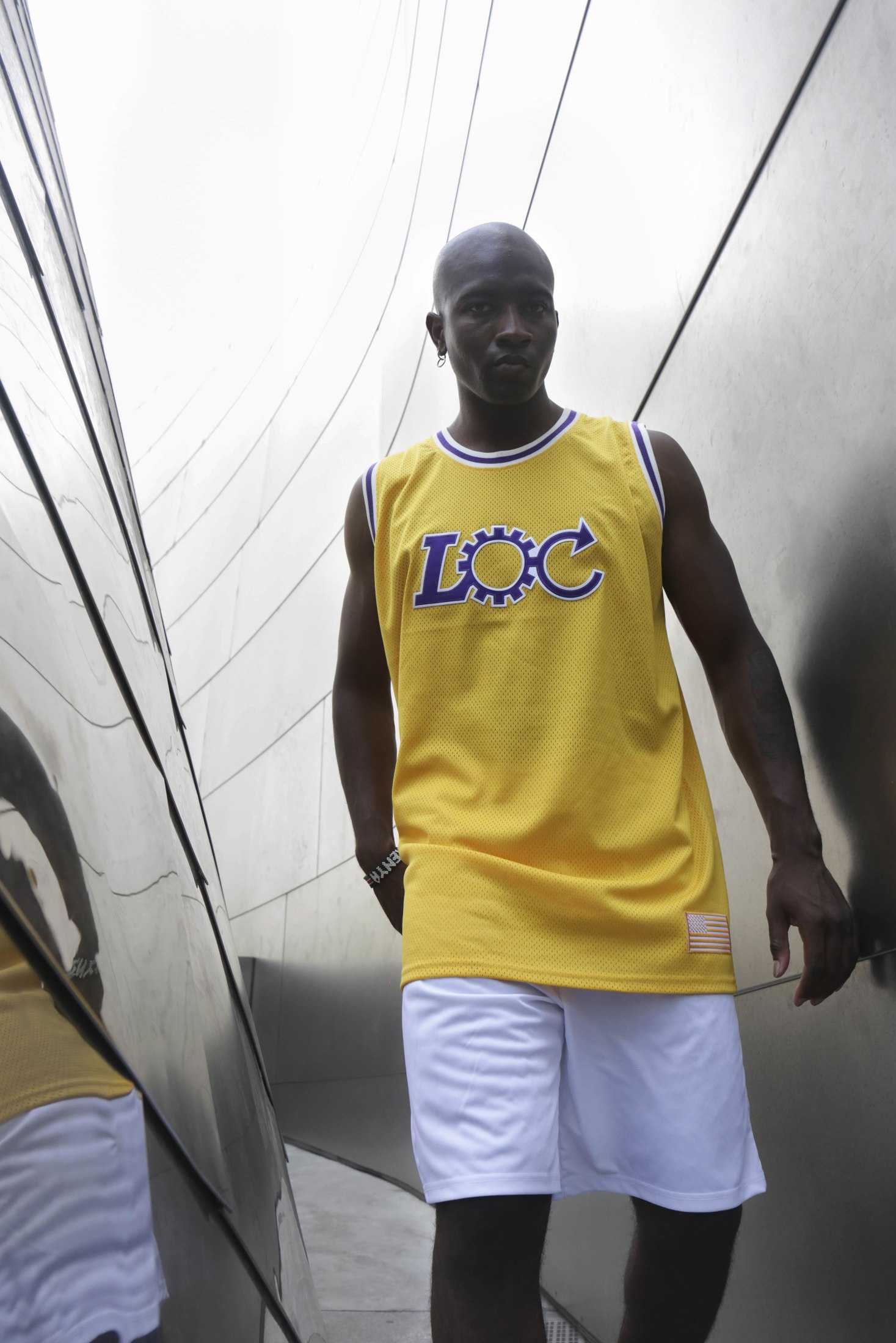 Model in a yellow LOC basketball jersey and white shorts